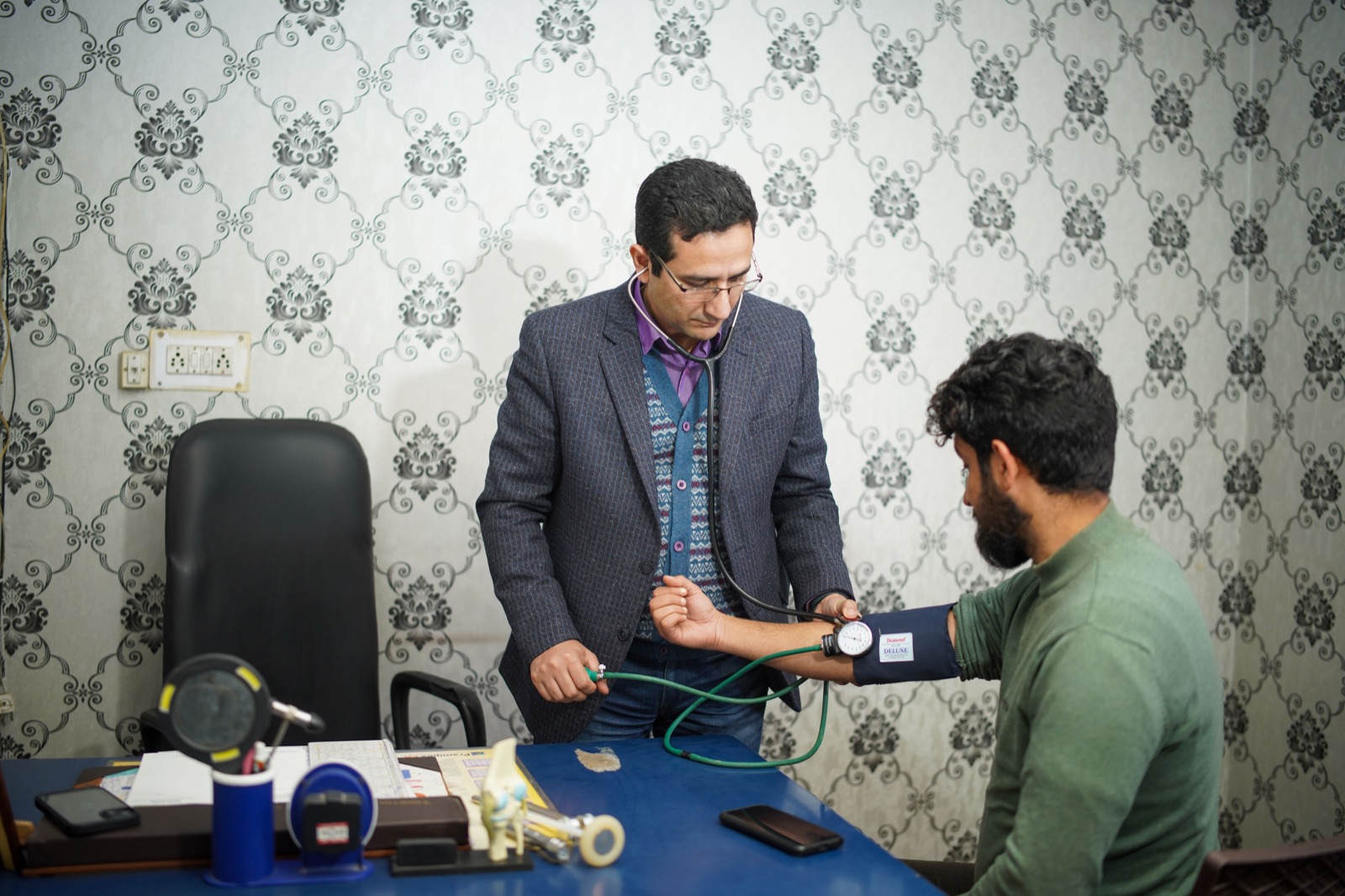 Doctor checking a young adult patient's blood pressure at home